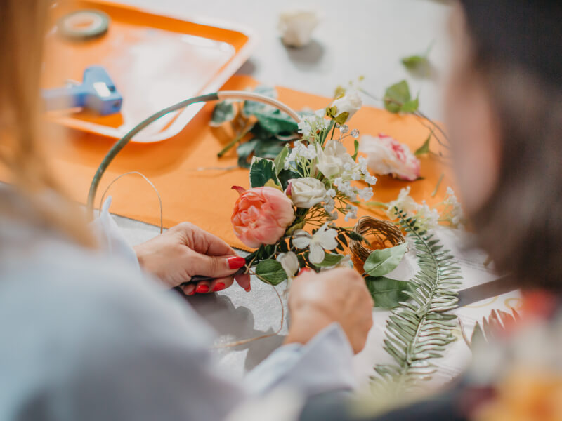 Someone using faux decorations in a wreath making class.